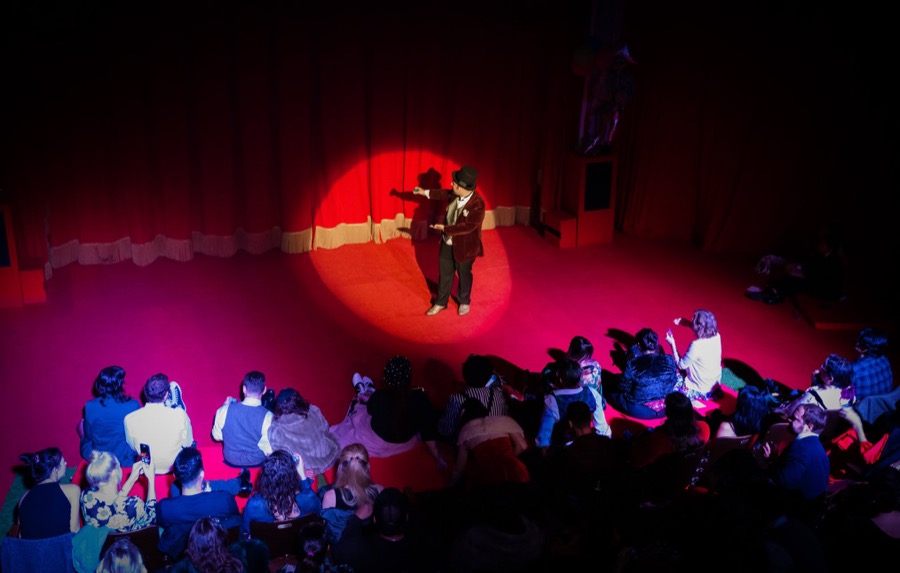 Performers in a red spotlight in front of a packed house